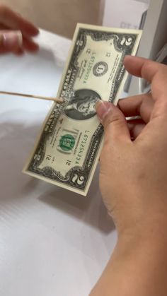 a person is holding a stick to a one dollar bill