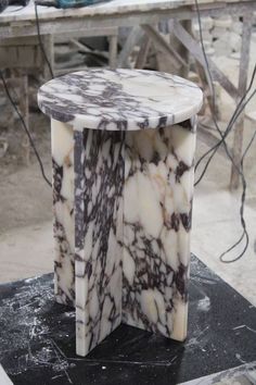 a white and brown marble table sitting on top of a black stand in a room