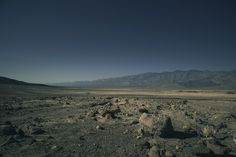 an empty desert with rocks and mountains in the background