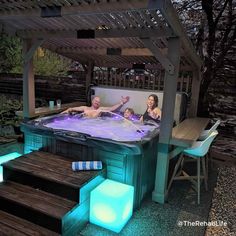 three people in an outdoor hot tub with blue lights on the side and steps leading up to it