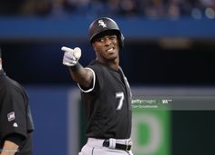 a baseball player holding a bat in his right hand and pointing to the side while another man looks on