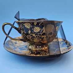 a tea cup and saucer on a blue background with gold designs in the middle