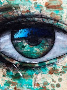 an eye painted on the side of a wall with blue and green paint all over it