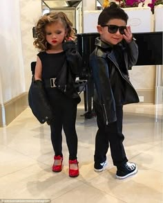 two young children dressed in black clothes and red shoes, standing next to each other