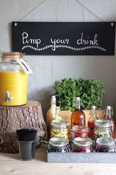 a wooden table topped with lots of bottles and jars filled with liquid next to plants