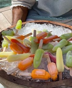 a wooden bowl filled with assorted fruit and veggies on skewers