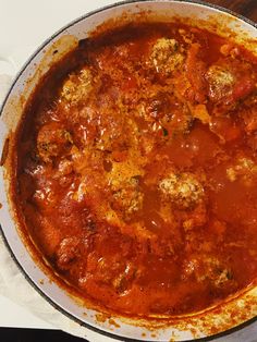 a pan filled with meatballs and sauce on top of a table