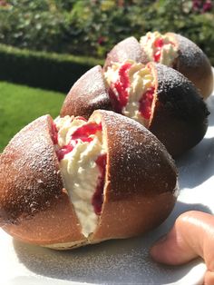 three rolls with cream cheese and strawberries on them are being held by someone's hand