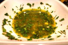 a white bowl filled with green vegetables and oil