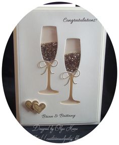 two champagne glasses with glitter on them are in front of a card that says congratulations