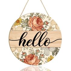 a wooden sign that says hello with flowers and leaves on the front, hanging from a rope