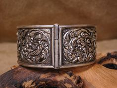 "Beautiful vintage sterling silver bangle cuff bracelet with intricate cut out flower design. The cuff has a nice tapered design. At it's widest point it measures 1 1/4\" wide and tapers down to 7/8\". The clasp is held together by a pin closure. A nice feature about the pin is it is not removable so there is no chance of losing it. The bracelet has an outside measurement of 7 3/4\". The bracelet is not stamped, but we do guarantee it to be sterling silver. It weighs 48 grams. Beautiful bracelet Engraved Antique Silver Cuff Bracelet For Weddings, Silver Engraved Wide Band Bangle, Engraved Cuff Bangle For Wedding, Wedding Engraved Cuff Bangle, Traditional Stamped Cuff Bracelet For Formal Occasions, Traditional Stamped Cuff Bracelet For Formal Wear, Ornate Hinged Cuff Bracelet As Gift, Elegant Carved Silver Cuff Bracelet, Ornate Hinged Cuff Bangle Bracelet