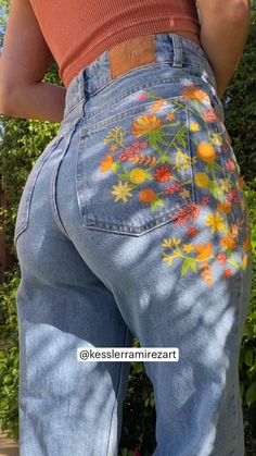 the back of a woman's jeans with flowers painted on it