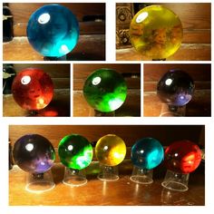 four different colored glass orbs sitting on top of a wooden table next to each other