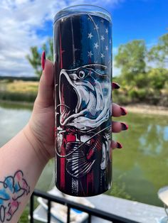 a woman's hand holding up a glass with an image of a fish on it