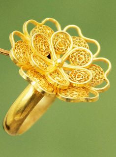 a yellow gold ring with intricate designs on the outside and inside, set against a green background