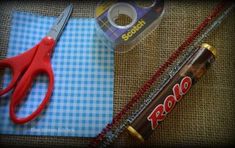 a pair of red scissors sitting on top of a table next to a roll of tape