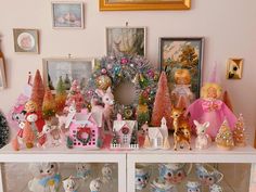 there are many small figurines on the shelf in front of the christmas tree