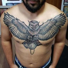 a man with an owl tattoo on his chest holding a pocket watch in his hand