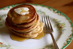 a stack of pancakes on a plate with butter and syrup drizzled on top