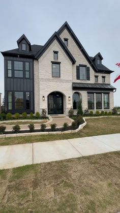 a large white brick house with black trim on the front and side windows is shown