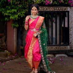 a woman in a pink and green sari posing for the camera with her hand on her hip