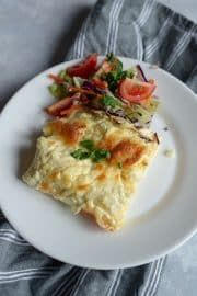 a white plate topped with an omelet covered in cheese and veggies