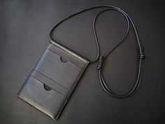 A stylish phone crossbody bag, minimally designed for functionality, for everybody and everyday.The body is made from Italian vegetan smooth leather, using leather cord for the shoulder strap.The shoulder strap is adjustable, you can wear it over a t-shirt, or over a heavy coat, it can suit any style.It carries your essentials and is perfect for travelling too.The front main pocket fits all sized smart phones, including plus sized phones and passport.Features two card slots on the back.Approxima Phone Sling Bag, Sling Bag Leather, Sling Bag Black, Leather Travel Wallet, Leather Weekender Bag, Leather Key Case, Leather Passport Holder, Leather Sling Bag, Heavy Coat