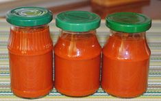 three jars of tomato sauce sitting on top of a table