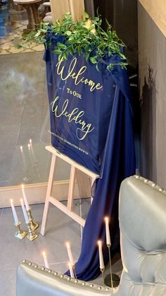 a welcome to our wedding sign in front of a blue chair with candles on it