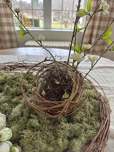 a bird's nest with moss and flowers on a table