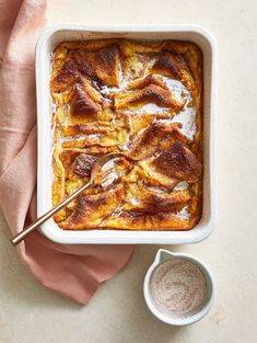 a casserole dish with meat in it on a table next to a spoon