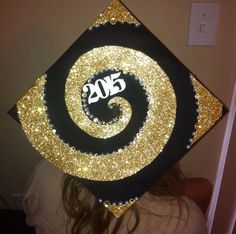 a woman wearing a graduation cap decorated with gold and black glitters that reads 350