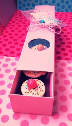 two cupcakes in a pink box on a polka dot tablecloth