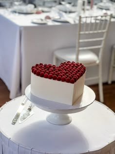 a heart shaped cake sitting on top of a table next to a white dining chair