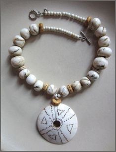 A string of creamy spheres of various shape and size mingle with ostrich egg-shell and milky glass from Africa. Tawny etched beads from Tibet add subtle contrast to the monochrome palette.  Age and wear have contributed to the rich patina of these cherished beads from the Himalayas.  An etched shell disc from Nagaland provides additional global cachet and seals the deal for artistic statement. A handmade silver toggle clasp from Thailand pulls this distinctive one-off design by Deborah Garner to Adjustable White Beaded Necklace With Natural Stones, Traditional White Necklaces With Natural Stones, White Jewelry With Wooden Beads, White Beaded Mother Of Pearl Necklace, White Jewelry With Round Wooden Beads, Adjustable White Wooden Beads, White Artisan Necklace With Wooden Beads, Artisan White Necklace With Wooden Beads, White Hand-strung Round Bead Necklaces