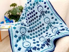 a blue and white afghan sitting on top of a chair next to a potted plant