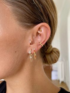 a woman wearing gold earrings with small stones on her ears and the back of her ear