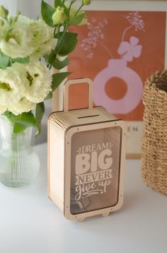 there is a small wooden box next to a vase with flowers in it on the table