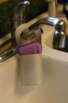 a toothbrush holder in the middle of a sink with soap and water on it