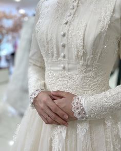 a woman wearing a white dress and holding her hands together