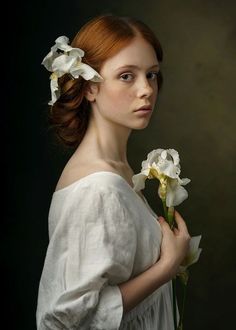 a woman with red hair wearing a white dress and holding flowers in her left hand