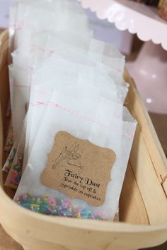 several bags of candy sitting in a wooden basket on top of a table with confetti and sprinkles