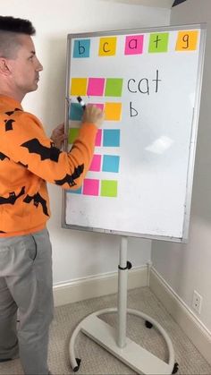 a man standing in front of a white board with writing on it and holding a marker