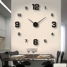 a clock that is on the wall above a dining room table with wine glasses in front of it