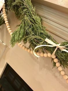 the garland is hanging on the mantle with white beads and pine needles attached to it