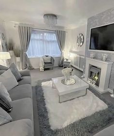 a living room filled with furniture and a flat screen tv mounted on the wall above a fire place