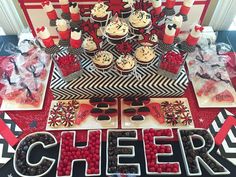 a table topped with cupcakes and desserts covered in red and black frosting