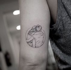 a woman's arm with a tattoo on it that has an image of two people hugging