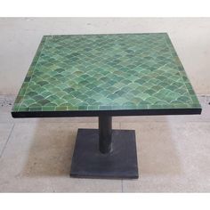 a green tiled table sitting on top of a metal base